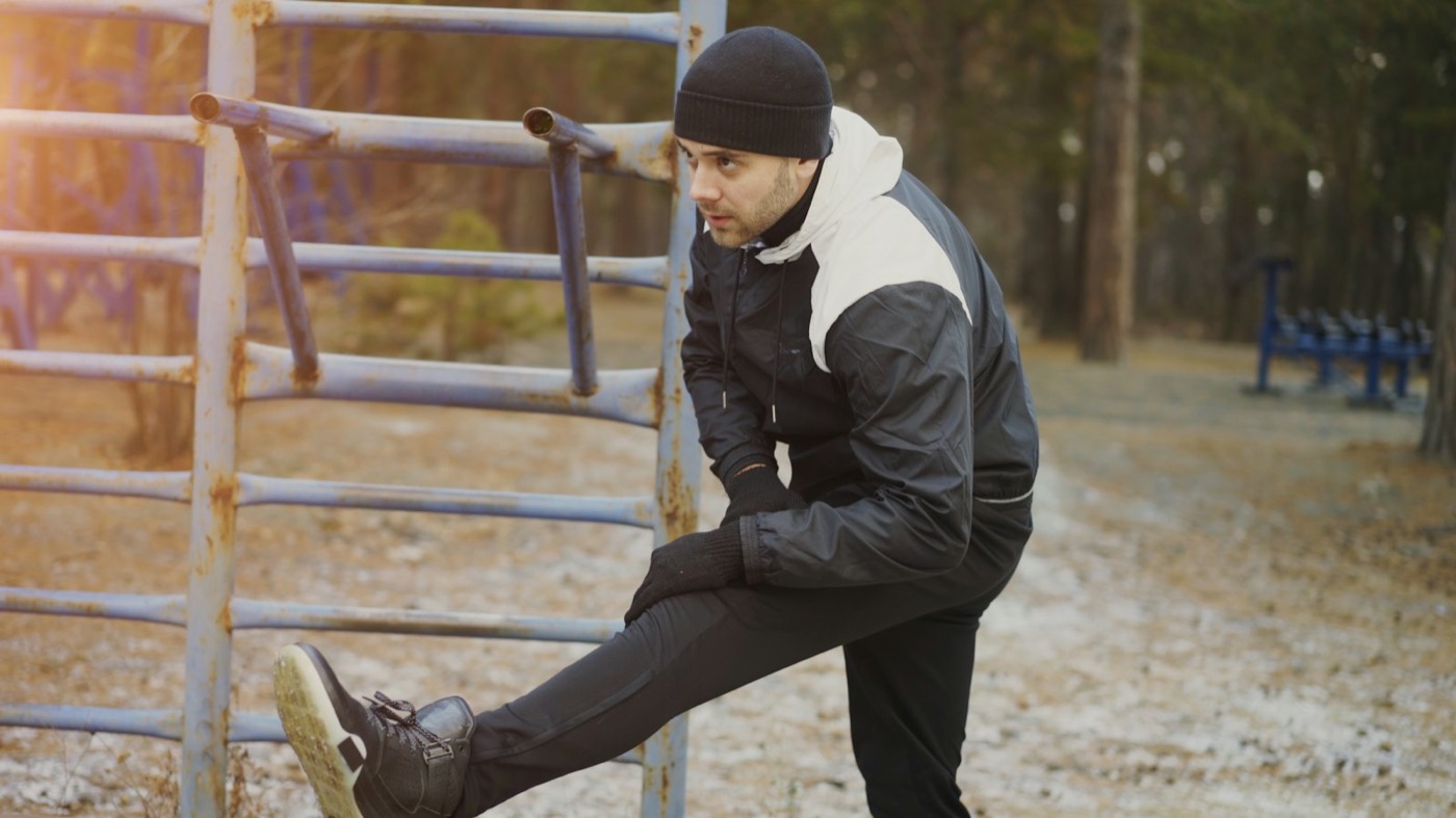 A man stretches his leg in a park before a run